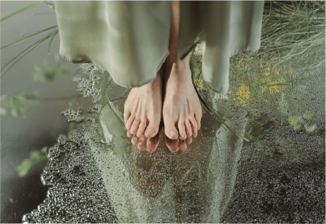 Paljaat jalat seisomassa veden äärellä – kehon ja mielen rauhoittuminen